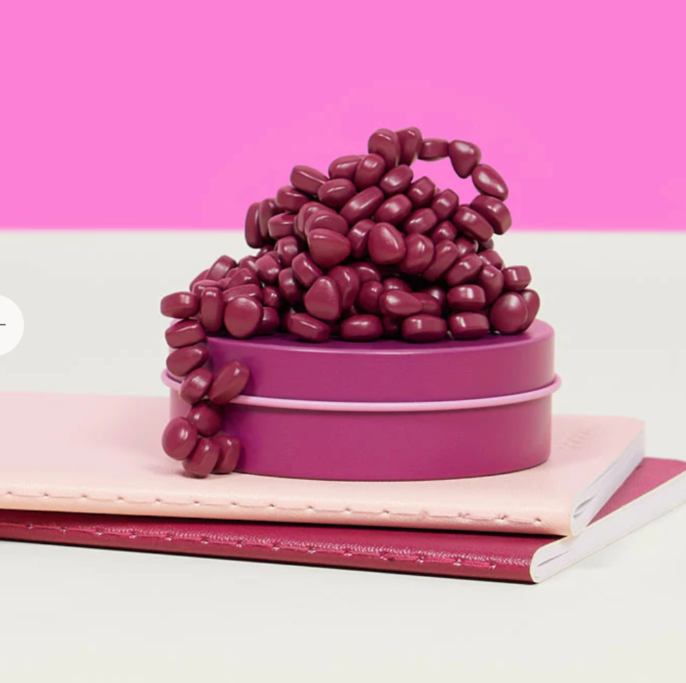 Speks. Matte. Mini Crags. Iris. magnetic putty in small tin, deep iris purple, displayed on notebooks.