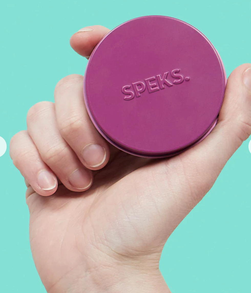 Hand holding a small purple tin of Speks. Matte. Mini Crags. Iris. magnetic putty for on-the-go use.