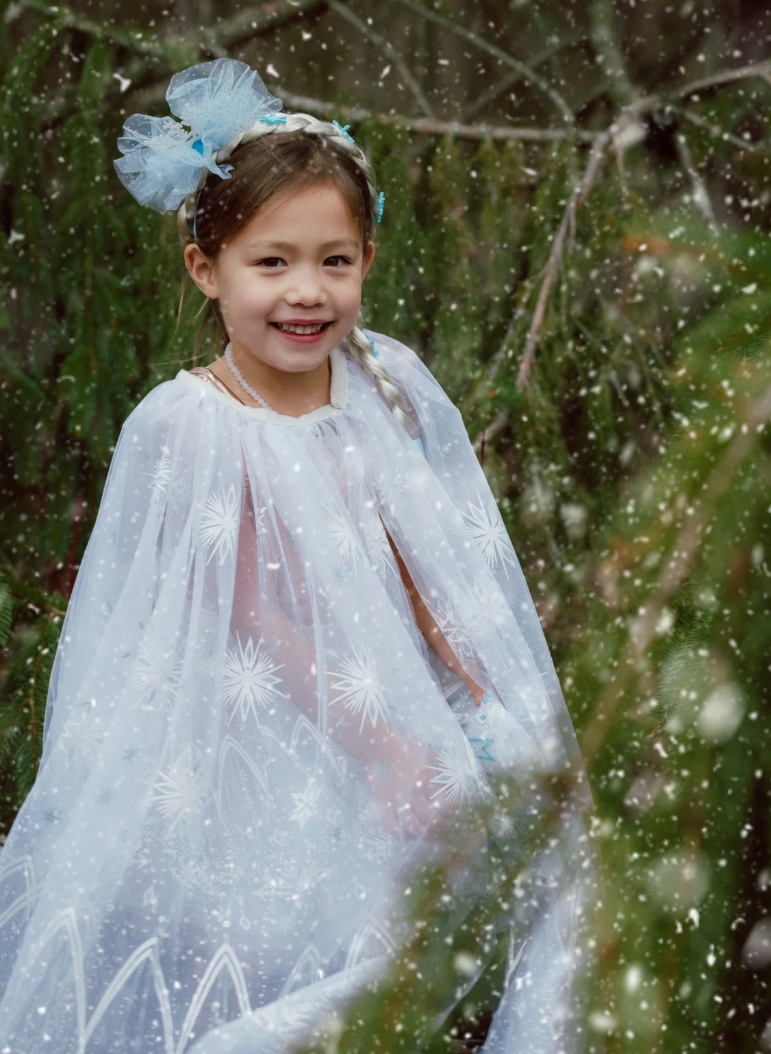 Winter Wonderland Cape Size 5-6 worn by smiling child outdoors with delicate icy snowflake designs and flowing white tulle.