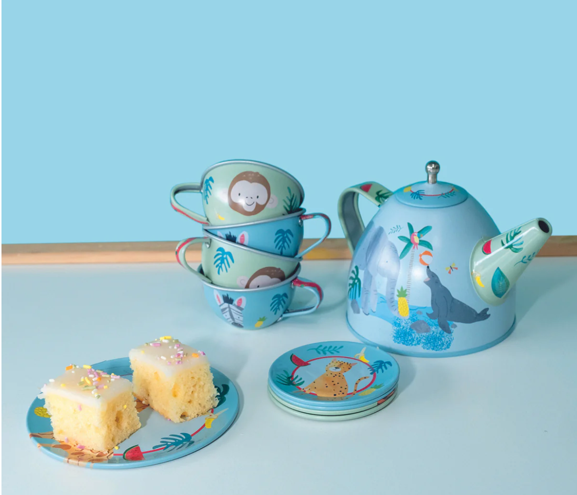 Tea Set | Jungle with animal-themed blue teapot, cups, saucers, plates, and two pieces of cake on a light background.