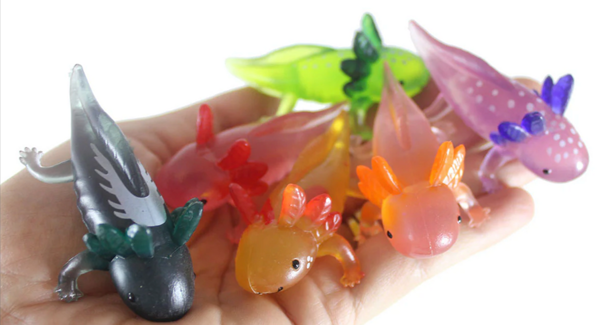 Little Axolotl soft plastic figurines in assorted colors shown on a hand, perfect for collectables and play.