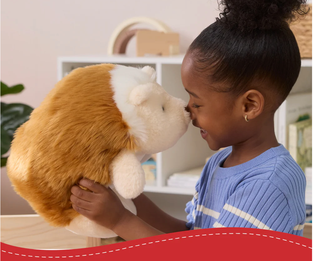 Child smiling and holding a plush Snuffles Hedgehog toy with soft, hazelnut-brown fur and hugging pose.