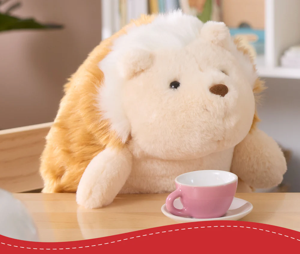 Snuffles Hedgehog plush toy sitting upright with soft beige and hazelnut-brown fur near a tiny pink teacup.