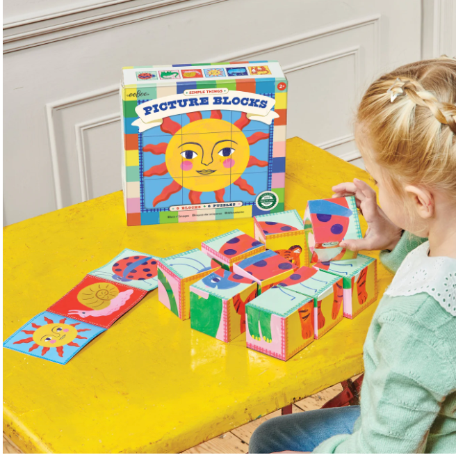 Child playing with Simple Things Picture Blocks on a yellow table featuring colorful stackable puzzles.