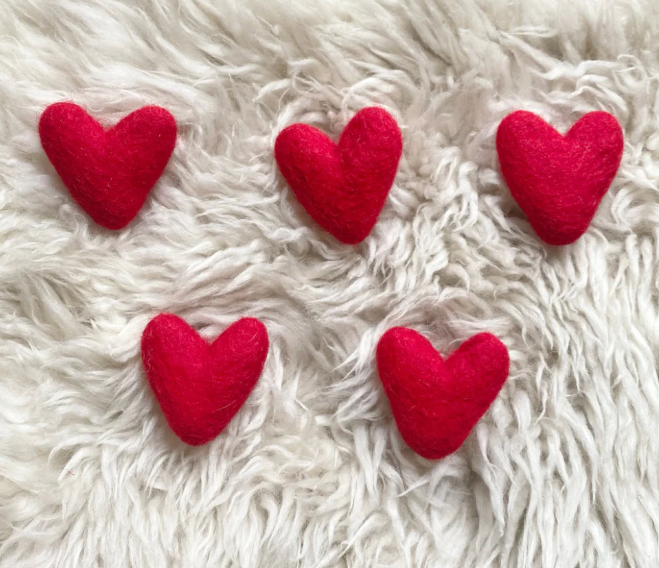 Felt Heart | Red handcrafted wool hearts displayed on soft white fur background, perfect for decor or gifts.