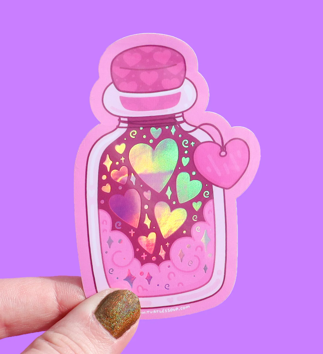 Hand holding a colorful Bottle of Hearts Sticker with shiny hearts and a pink background, scratch-resistant and waterproof.