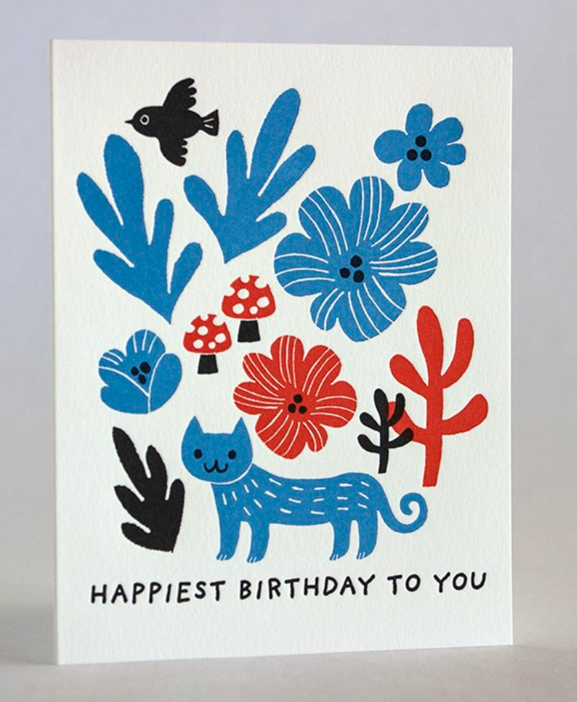Cat with Flowers Birthday Card featuring colorful blue and red flowers, a blue cat, and a black bird on white paper.