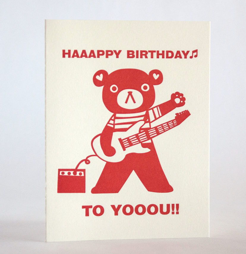 Rocking Guitar Bear Birthday Card featuring a red bear playing guitar with birthday message on recycled white paper.