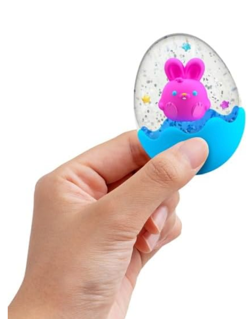 Hand holding the NeeDoh Squeezter Egg with confetti and a pink bunny inside a blue shell, sensory toy.