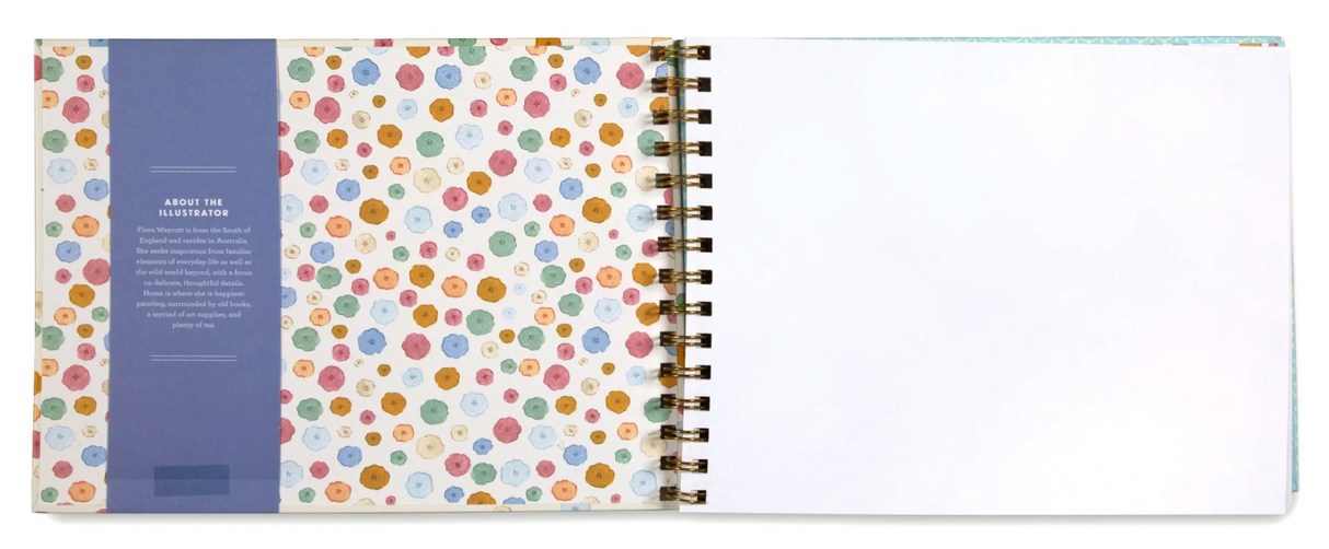Artist Sketchbook | Flora open to blank page, showing colorful floral patterned inside cover and spiral binding.