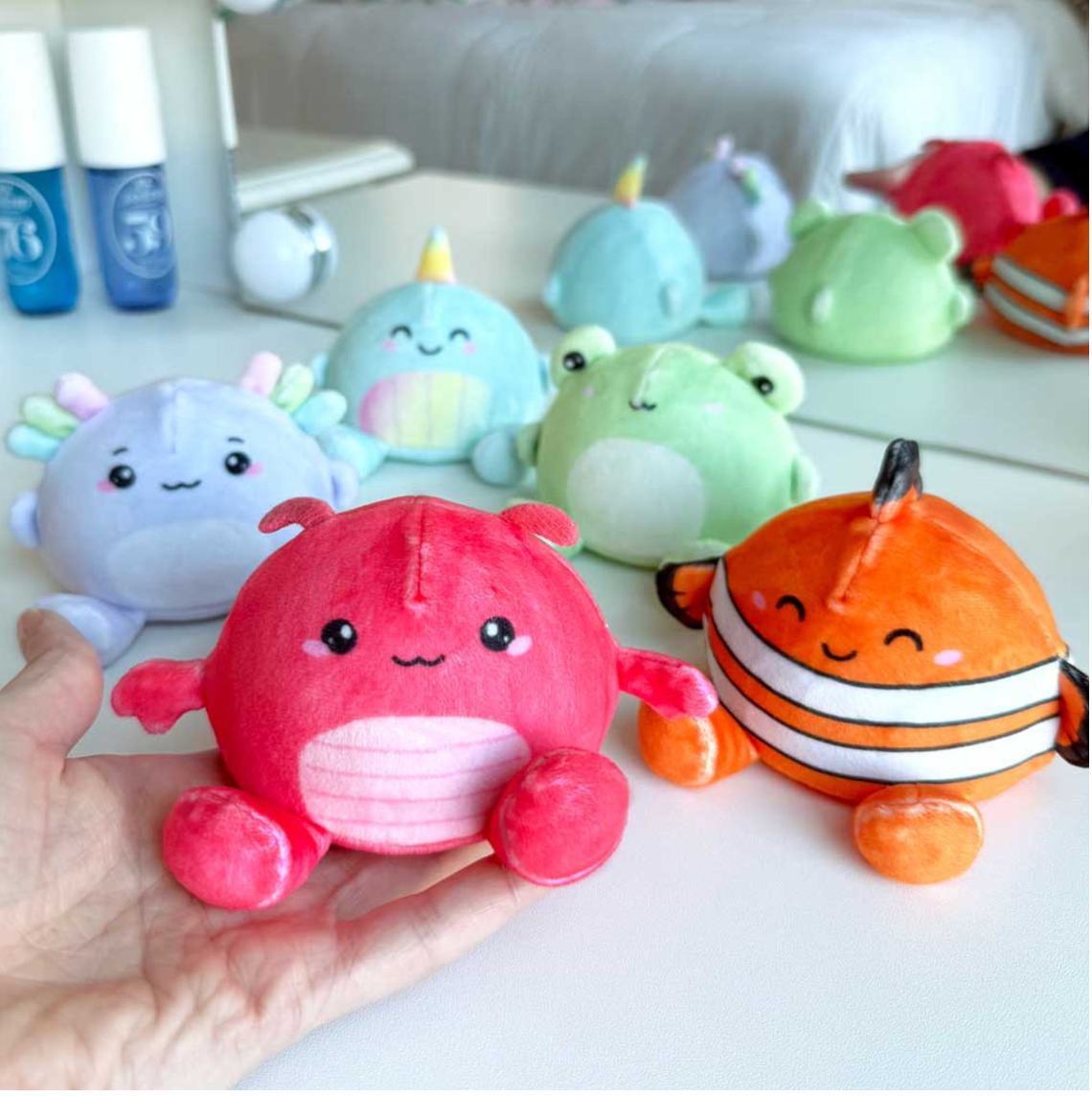 Sugar Squisher Plush | Seafriends Edition showing colorful, soft, squishy sea creature plush toys in hand and on table.