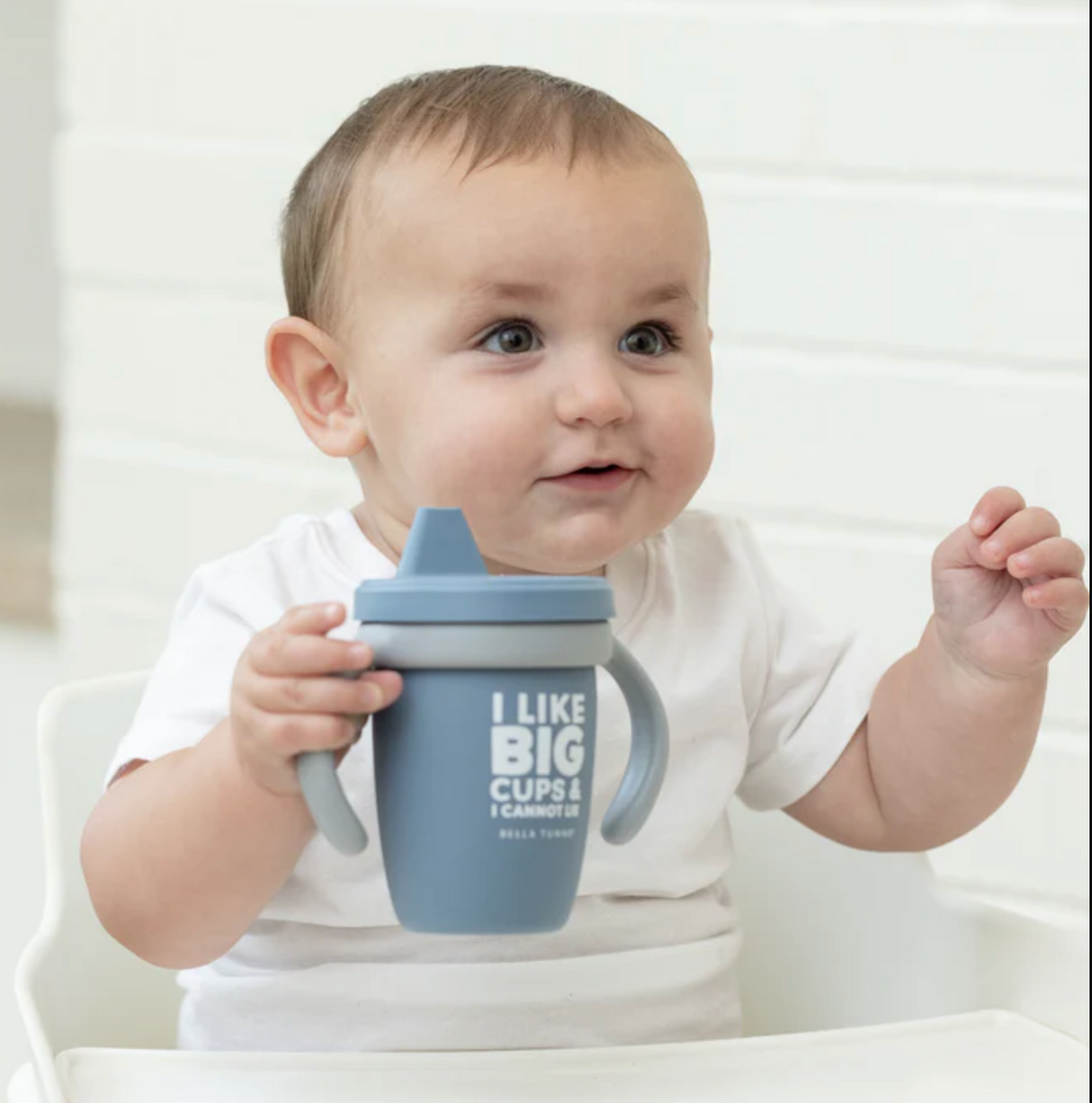 Baby holding blue Happy Sippy Cup | I Like Big Cups with handles, perfect for toddlers learning to drink independently.
