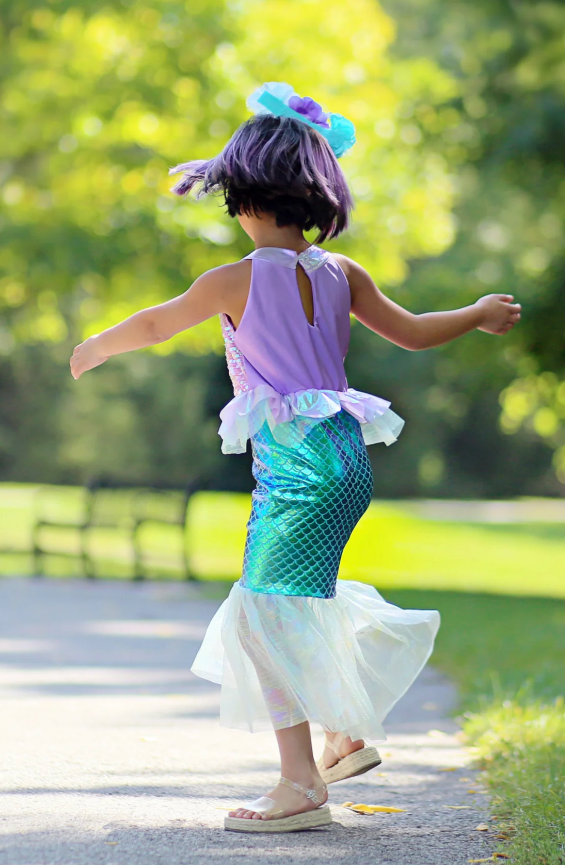 Girl twirling outdoors wearing the Misty Mermaid Dress with a purple top and teal mermaid-style skirt.