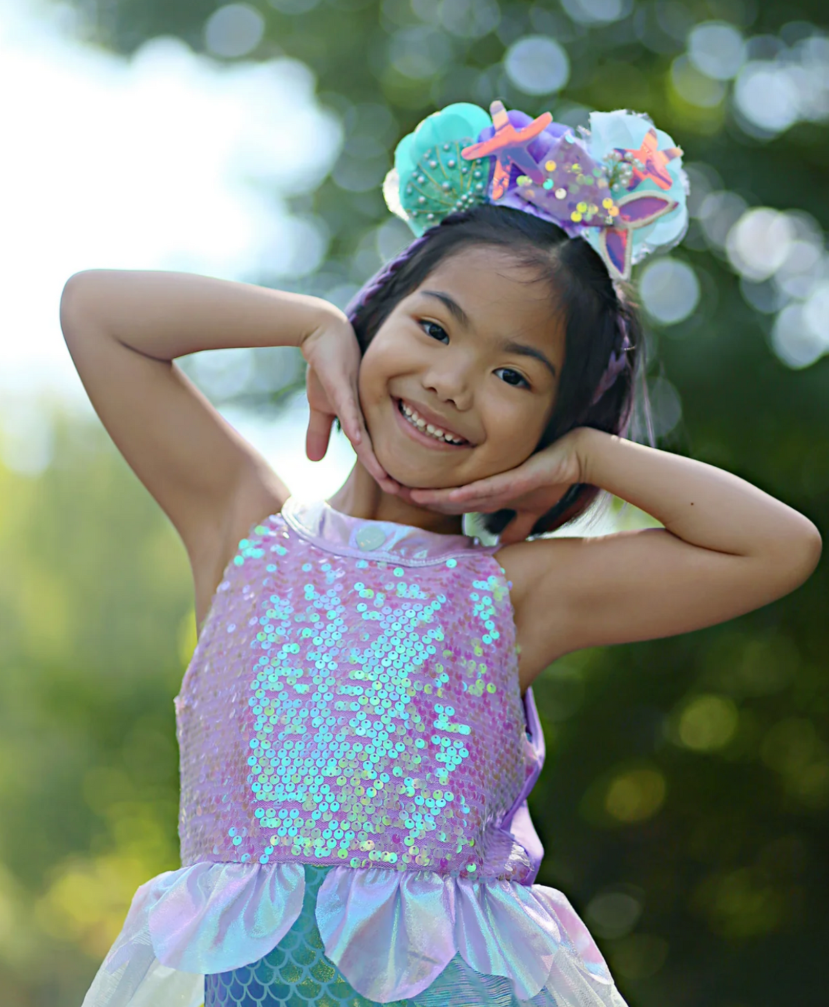 Young girl smiling and posing outdoors wearing the Misty Mermaid Dress with sequins and tulle skirt.