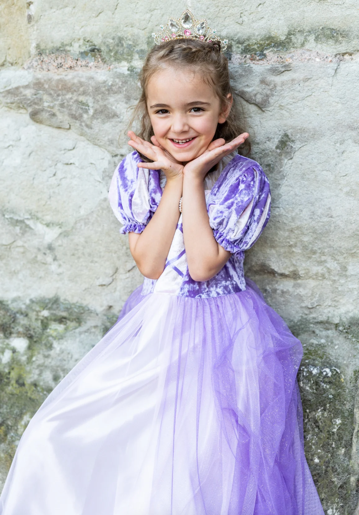 Young girl smiling in the Once Upon a Tower Princess Dress with purple velvet top and layered tulle skirt.