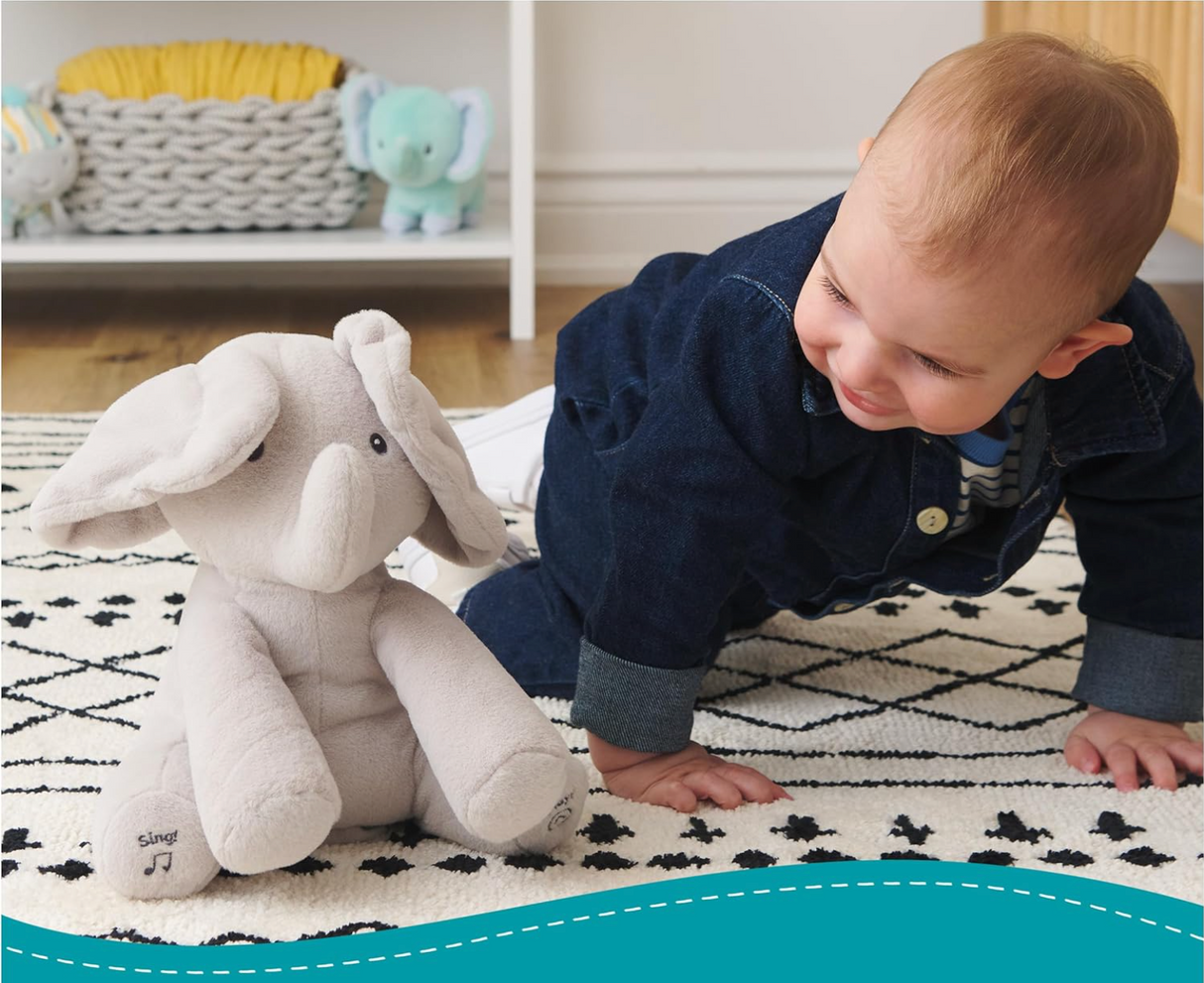 Peek-a-Boo Flappy the Elephant soft gray singing toy with floppy ears, engaging baby in tactile play on a patterned rug.