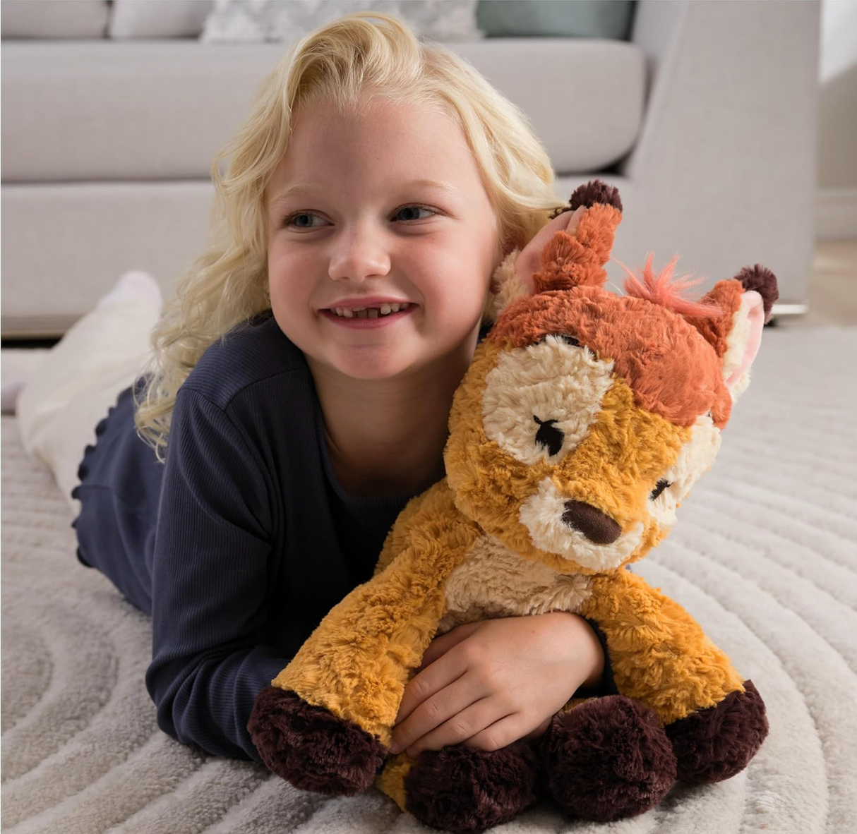 Young child cuddling a soft plush toy Cozys Bambi featuring textured brown and cream fabric with embroidered details.