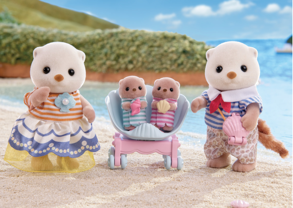Sea Otter Family with mother, father, and two babies in shell pram on sandy beach, playful outfit details visible.