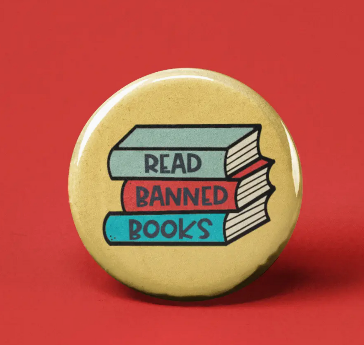 Button | Read Banned Books featuring a stack of colorful books with a message supporting freedom of expression and literature.