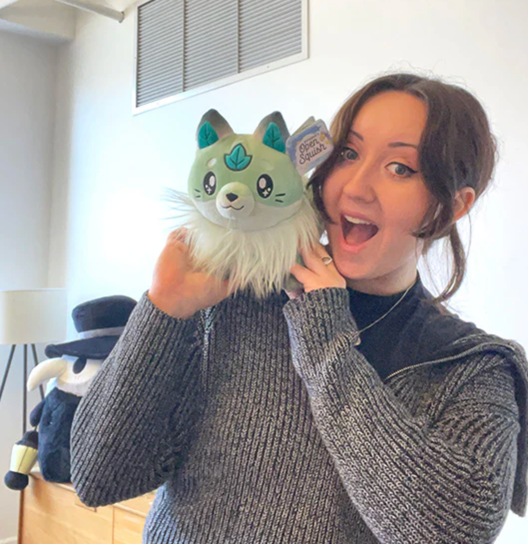 Person holding a Leafy Fox Mini plush with green woodland colors and a friendly expression indoors.