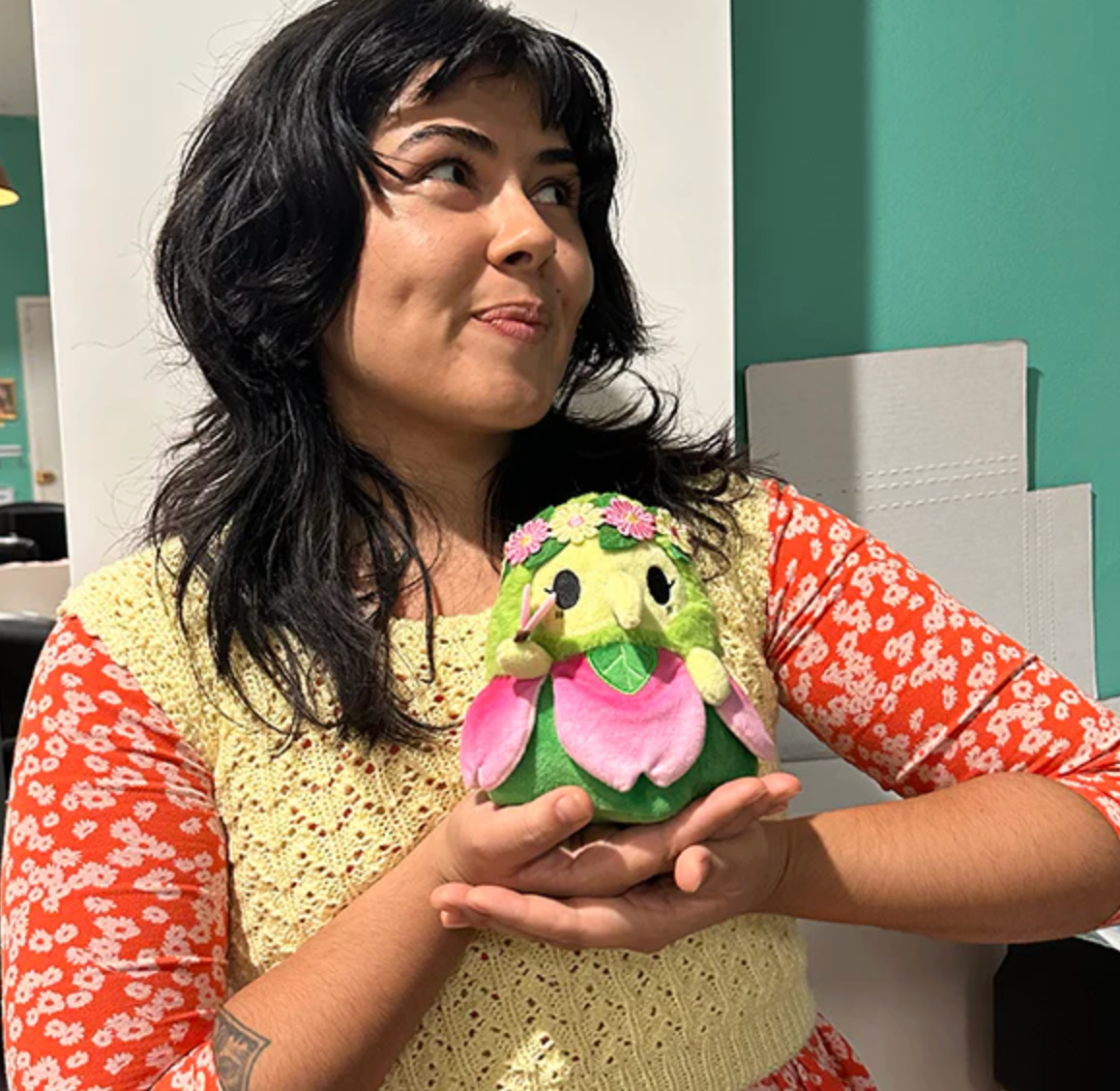 Person holding Alter Ego | Plague Doctor Nymph plush toy with green and pink nature-inspired design indoors.