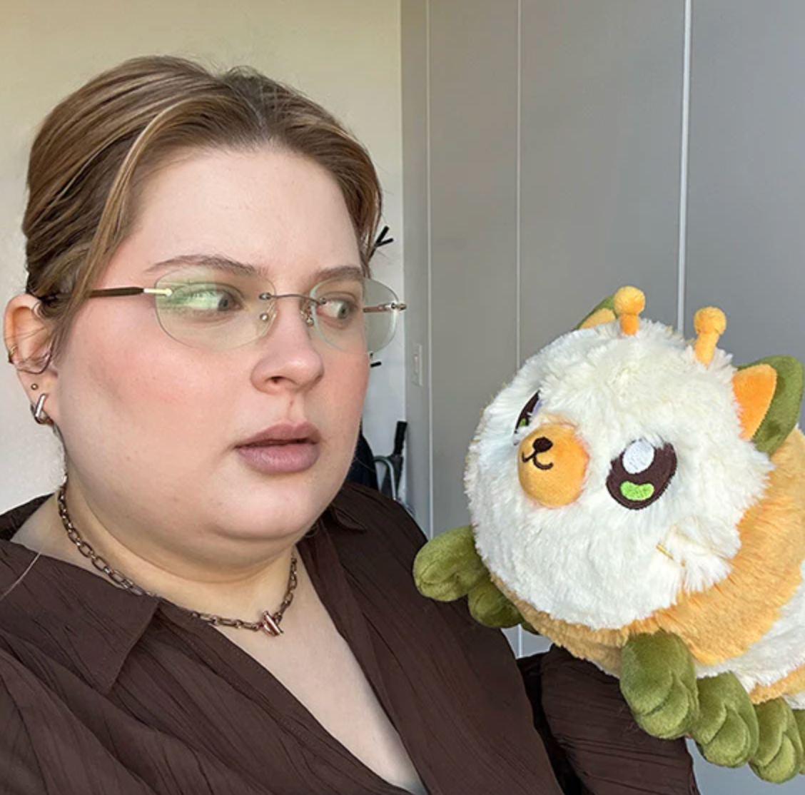 Person holding and looking at a fuzzy Kittypillar/Caterpillar Mini plush toy with many paws and leaf-like feet.