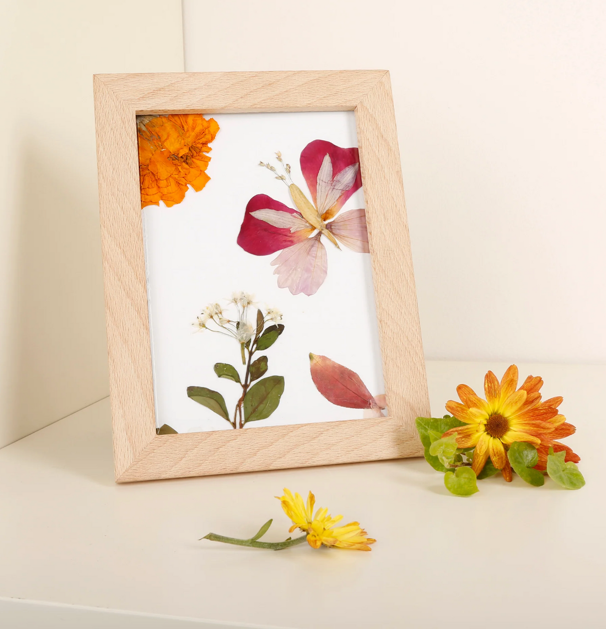 Huckleberry Pressed Flower Frame displaying colorful pressed flowers in a natural wood frame on a white surface.