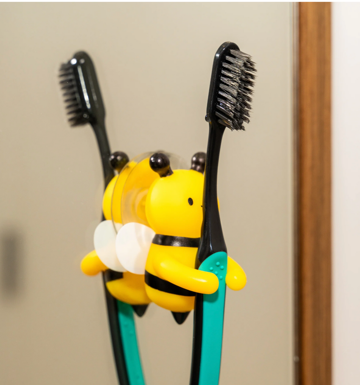Toothbrush Holder | Bumble Bee holding two toothbrushes with a cheerful yellow and black bee design mounted on a bathroom mirror.