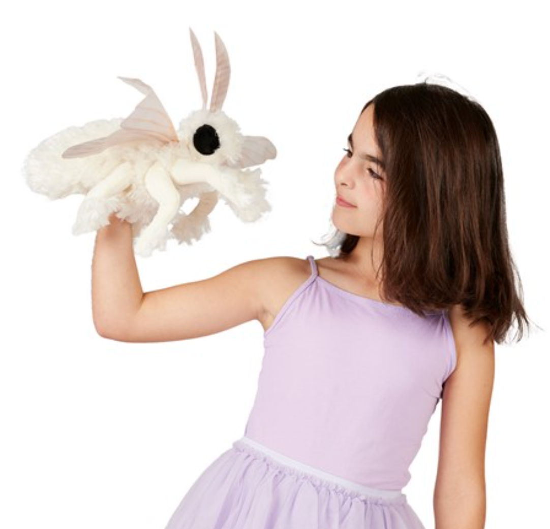 Girl in lavender dress holding a Poodle Moth Puppet with fluffy white body and large antennae.