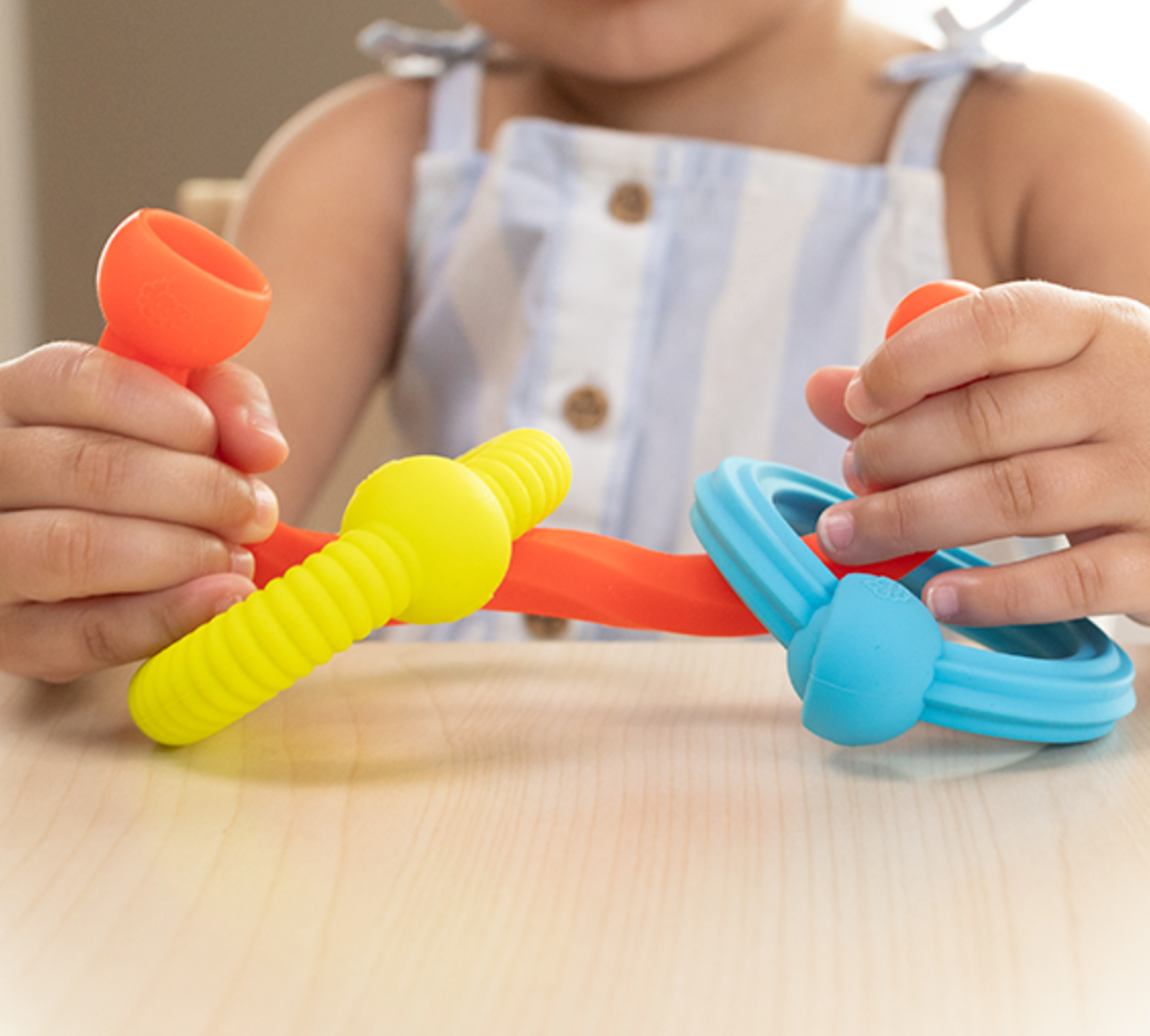 Child holding colorful textured silicone links of Plip Grips toy designed for sensory play and fine motor skills development.