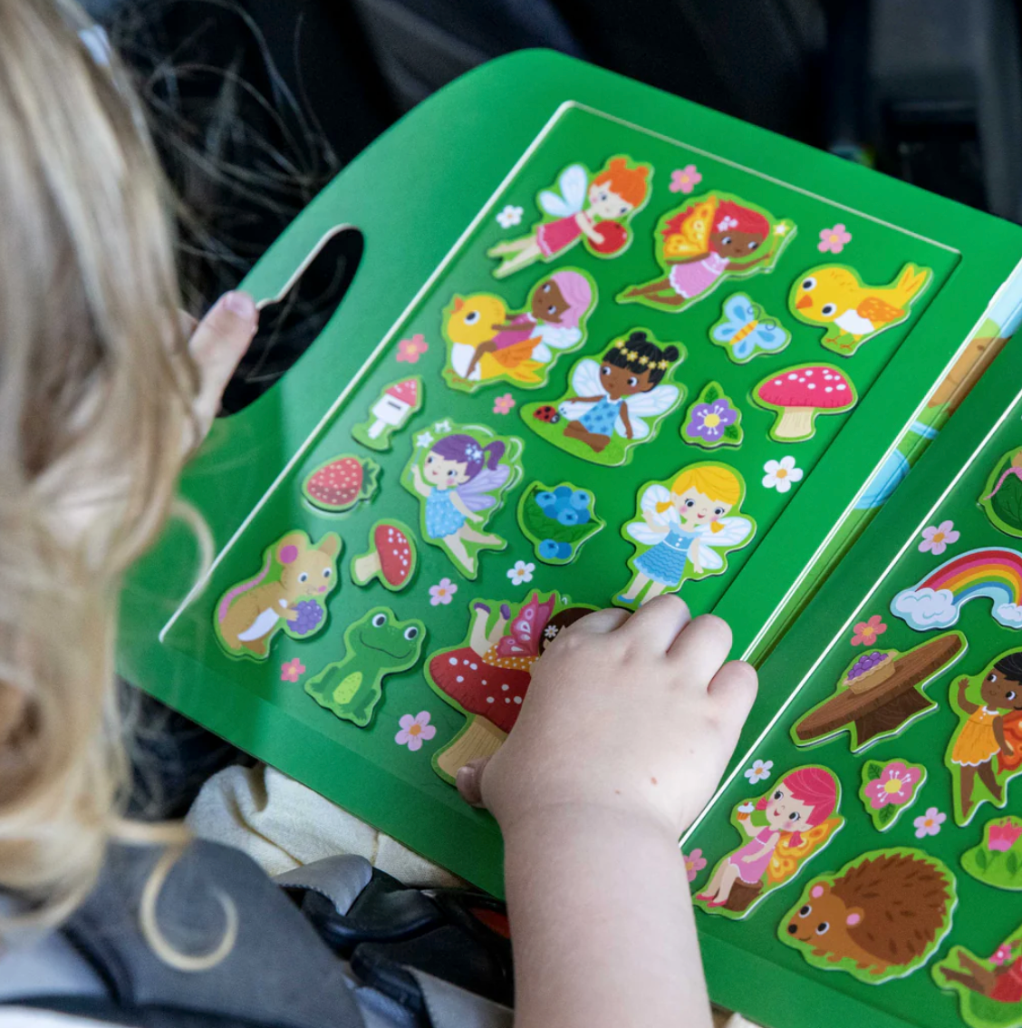 Child playing with colorful forest fairy magnets in the Magna Carry | Forest Fairies set on a green background.