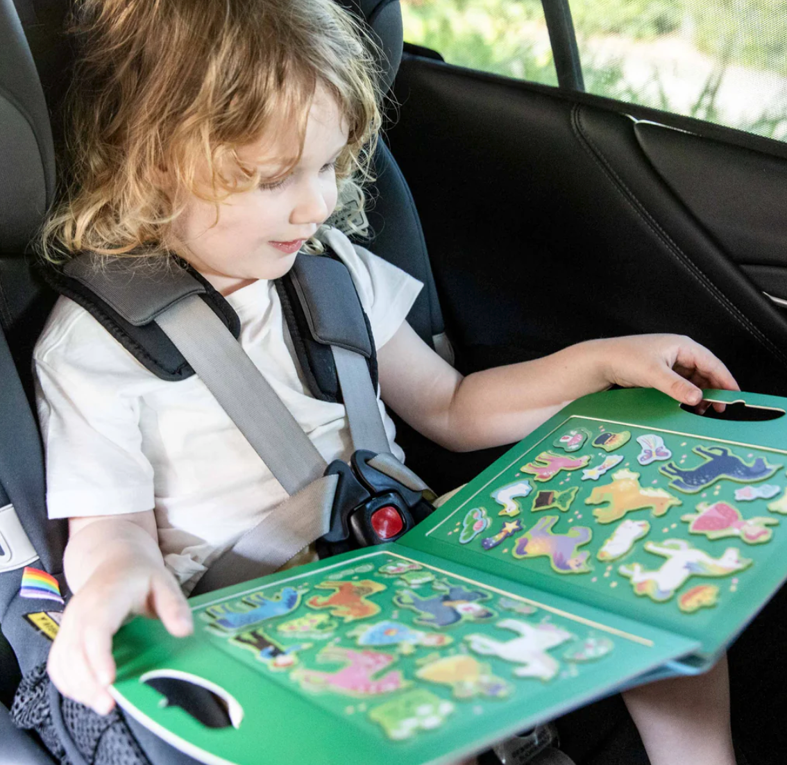 Child playing with magnetic fold-out play scene featuring unicorns in the Magna Carry | Unicorn Kingdom set in car seat.