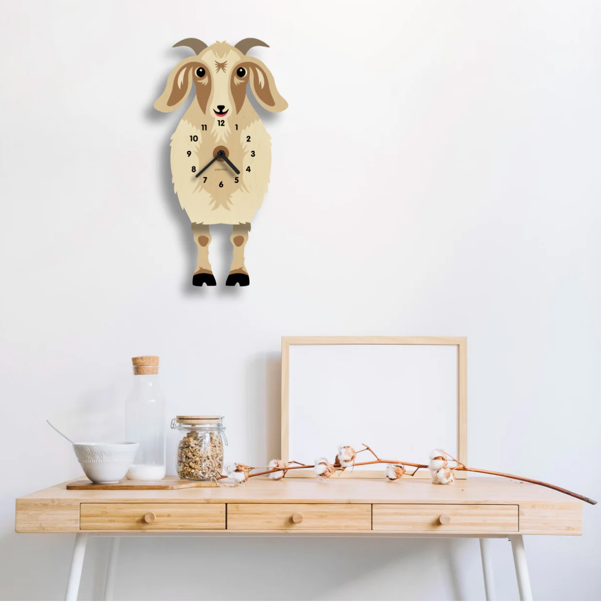 Wood Pendulum Clock | Goat Greta hanging on wall above wooden table with kitchen items and cotton branch