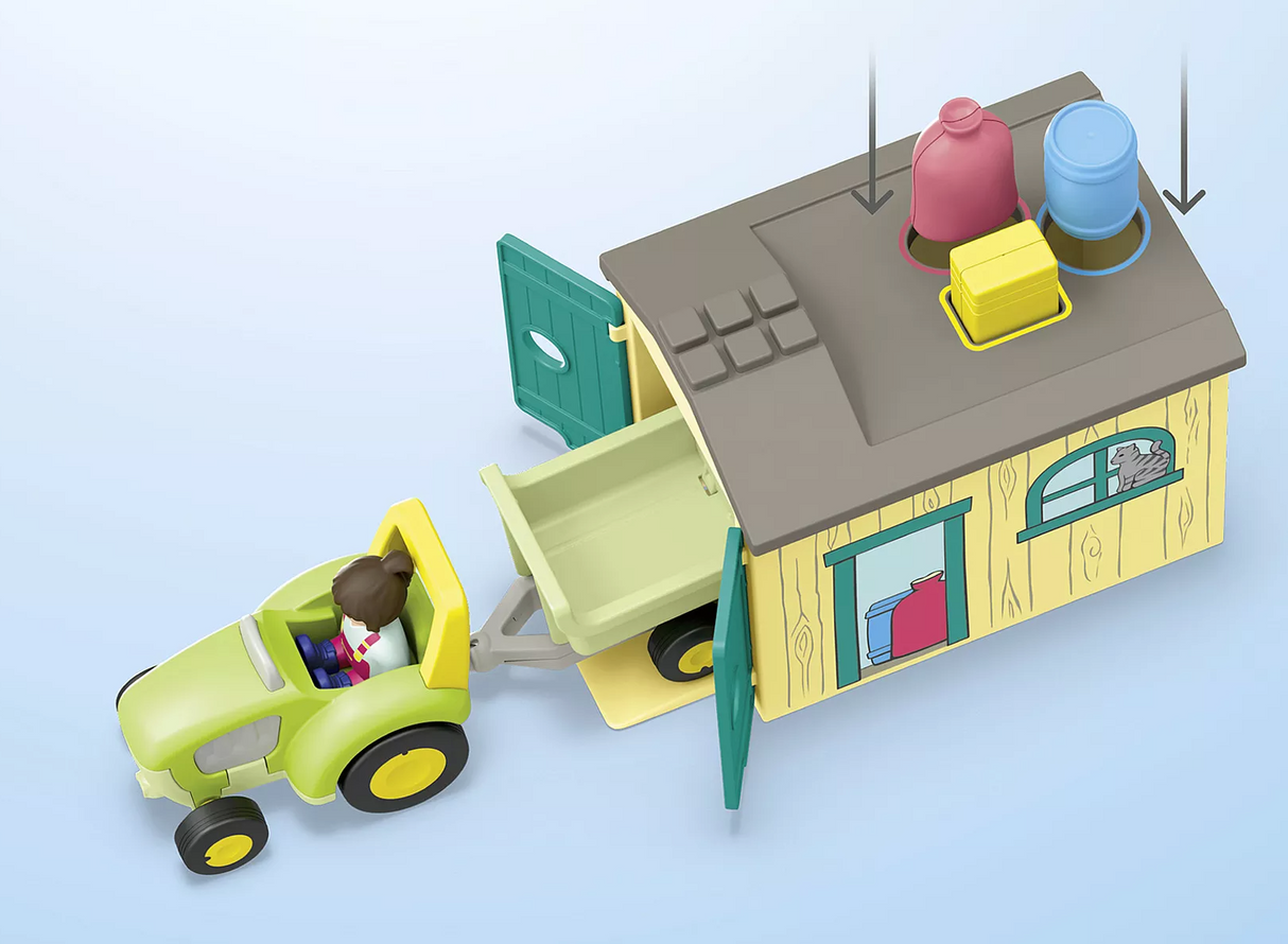 Junior | Farm Adventure with Tractor showing child figure driving green tractor with trailer next to open barn playset and accessories.