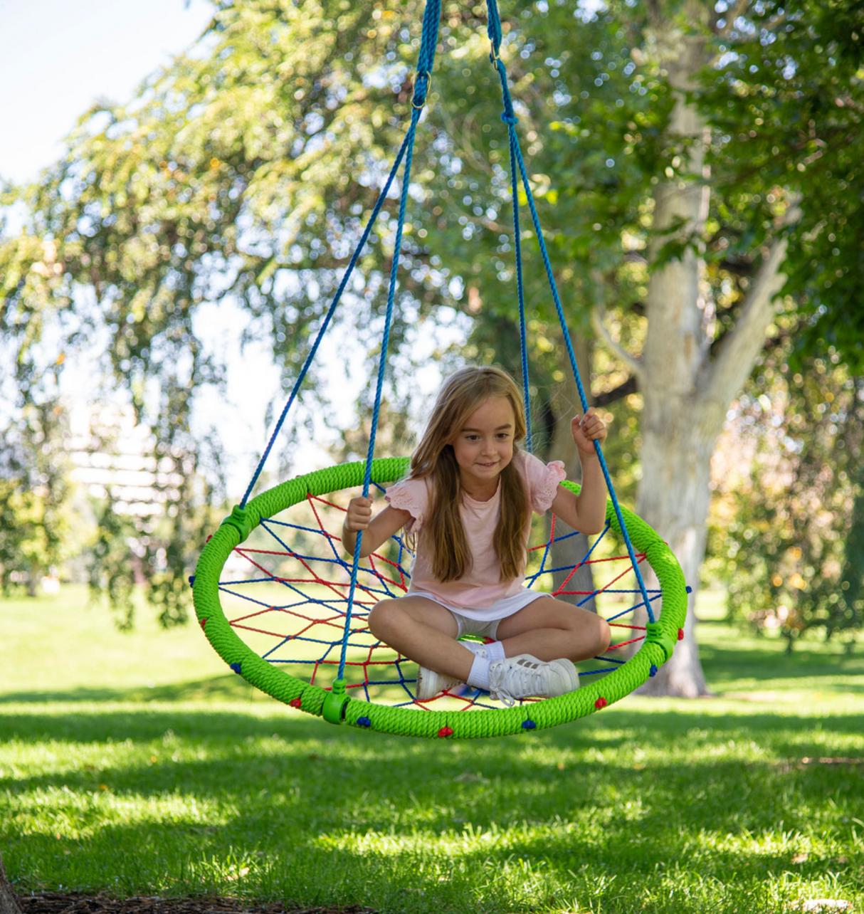 Dreamcatcher Swing with colorful woven design, hanging outdoors with a child enjoying the fun and relaxing moment.