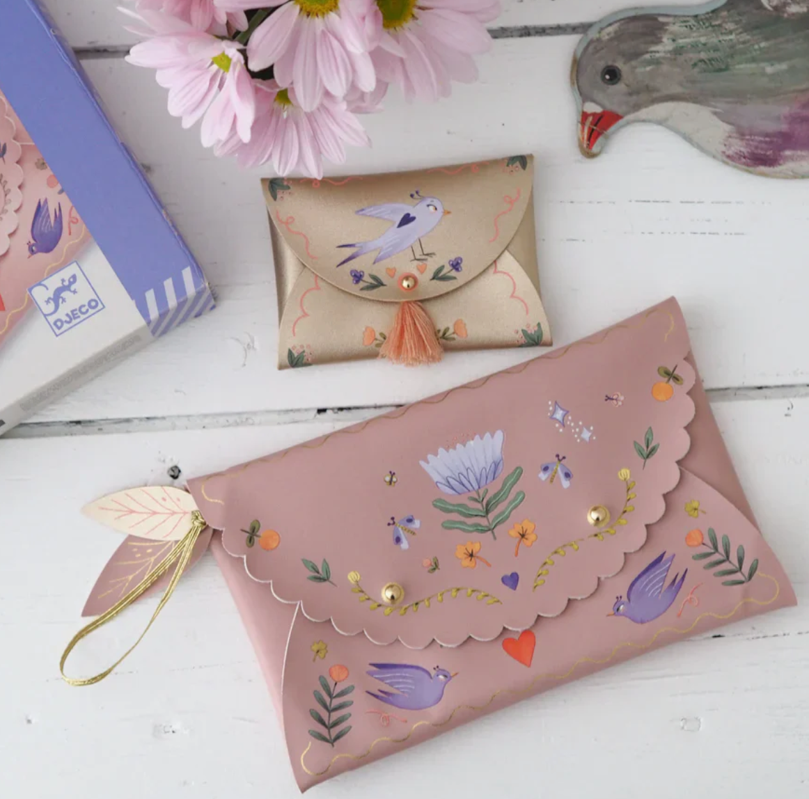 DIY Sweet Fashionista Pouches featuring two faux leather purses with colorful bird and flower decals on a white table.