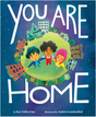 You Are Home book cover with children holding hands on a small green planet surrounded by homes and buildings at night.