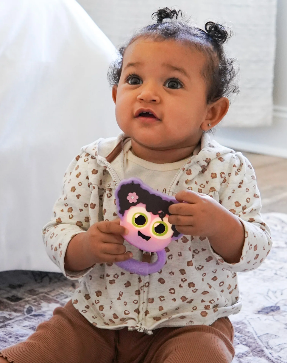 Baby holding Glo Pals Light Up Rattle Purple with glowing eyes, promoting sensory and motor skill development.