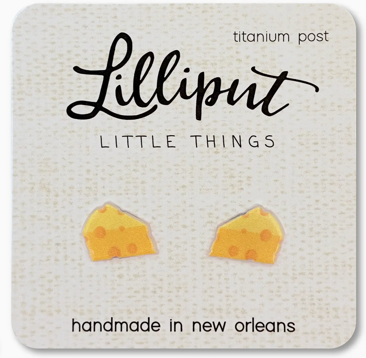Small handmade cheese wedge stud earrings with titanium posts on a textured card from Lilliput Little Things