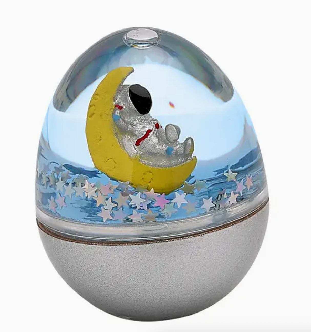 Clear snow dome with an astronaut figure sitting on a yellow crescent moon surrounded by floating star-shaped glitter