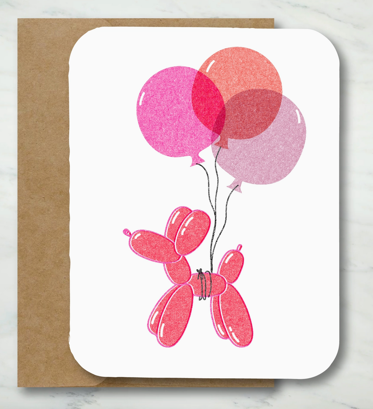 Folded card featuring a pink balloon dog holding three colorful balloons with a recycled Kraft envelope background