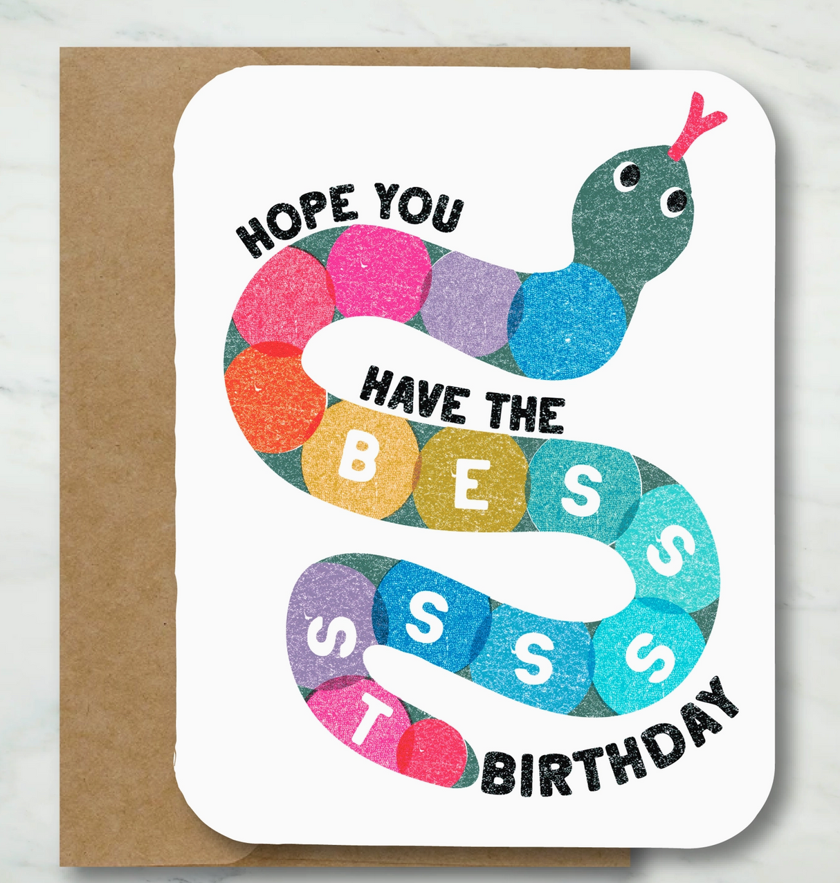 Colorful worm illustration with text wishing a "Have the Besssst Birthday" on a textured card with kraft envelope