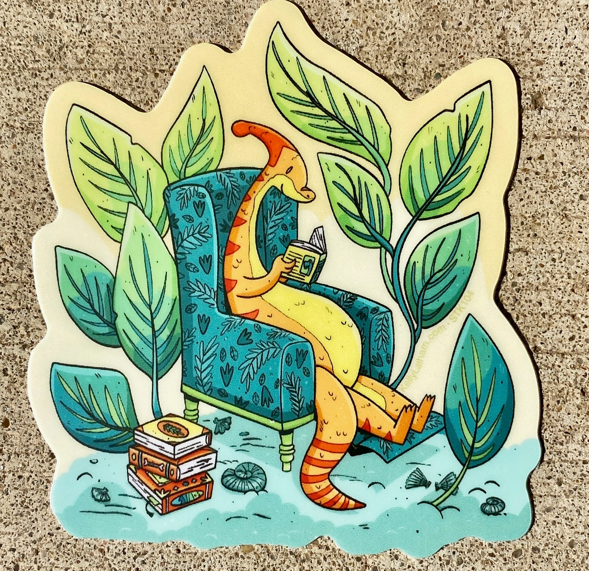 Dinosaur character reading a book while sitting on a patterned armchair surrounded by large green leaves and stacked books.