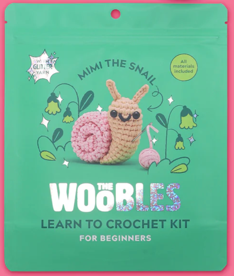 Green package featuring Mimi the Snail crochet kit with cute snail holding a crochet hook and pink shell yarn ball.
