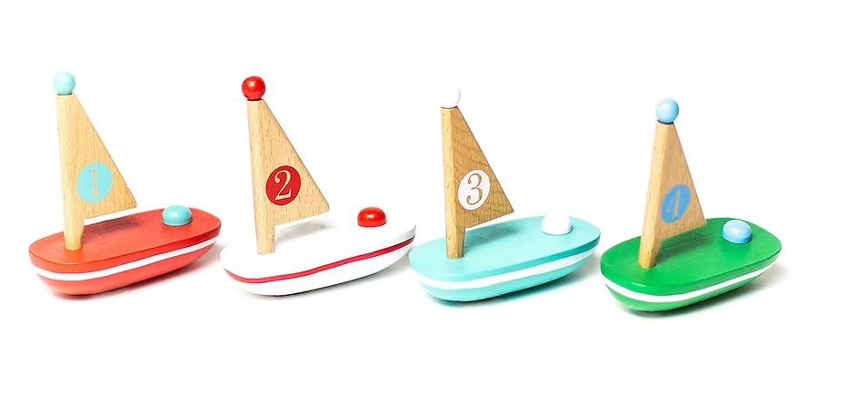 Four colorful wooden sailboats with numbered sails arranged side by side on a white background