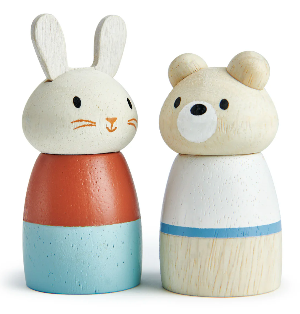 Wooden toy figures of a rabbit and bear with painted faces and colorful outfits standing side by side