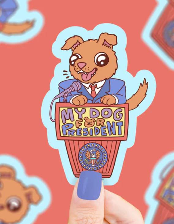 Sticker of a happy cartoon dog in a suit standing at a podium that says My Dog for President on a coral background