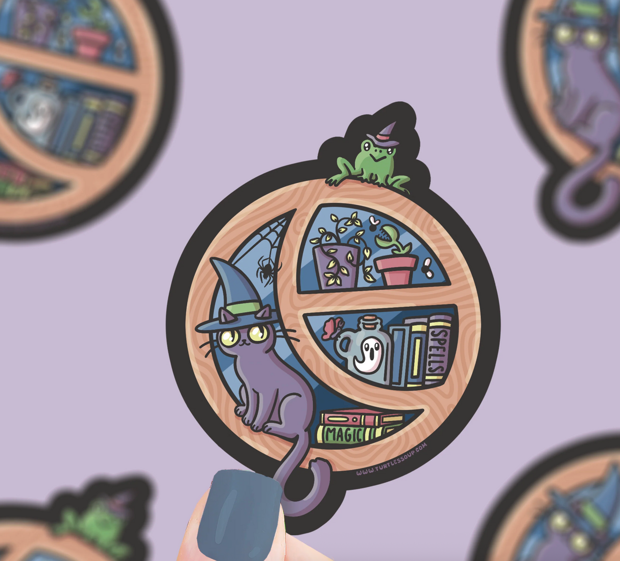 Cute Halloween window sticker showing a witch’s cat, frog, plants, and magical books in a round window frame.