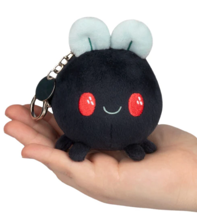 Small plush Micro Fly keychain with cheerful face held in hand, soft and quiet without buzzing sound.