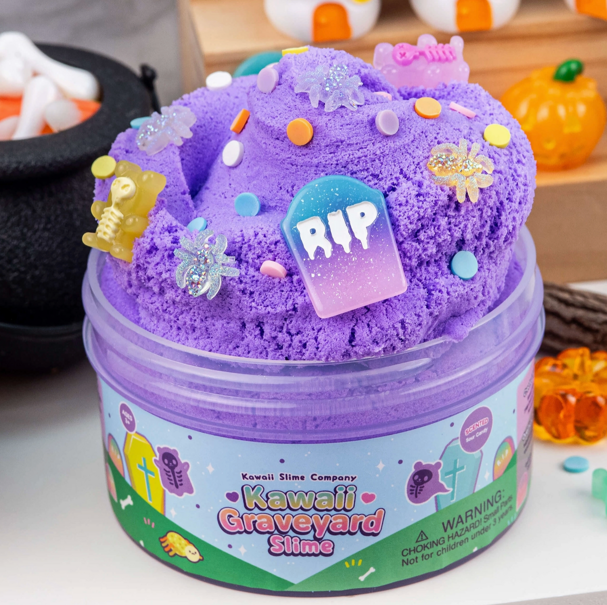 Purple cloud creme slime with colorful confetti and spooky graveyard-themed charms in clear container on table